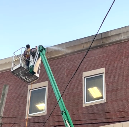Commercial pressure washing - crew using lift to clean multi-story building exterior